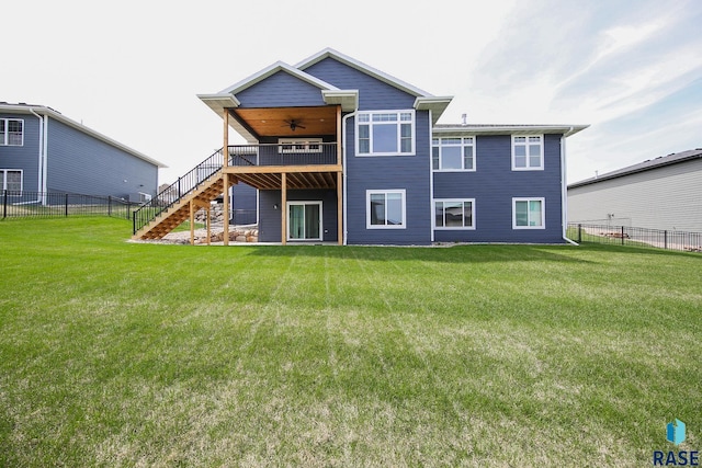 rear view of property with a yard, a ceiling fan, stairs, and a fenced backyard
