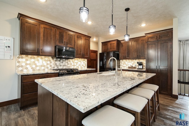 kitchen featuring baseboards, dark wood finished floors, a kitchen bar, and stainless steel appliances