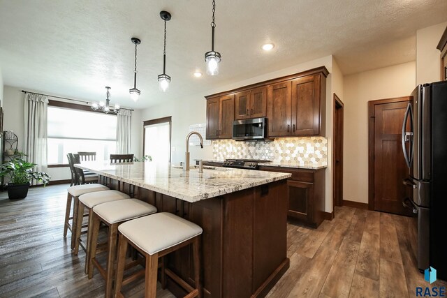 kitchen featuring decorative backsplash, a kitchen breakfast bar, a sink, stainless steel microwave, and freestanding refrigerator