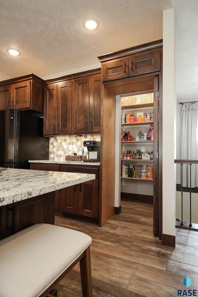 interior space with tasteful backsplash, freestanding refrigerator, dark wood finished floors, and a textured ceiling
