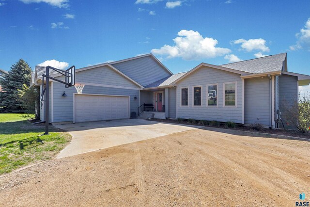 ranch-style house featuring a shingled roof, an attached garage, and driveway