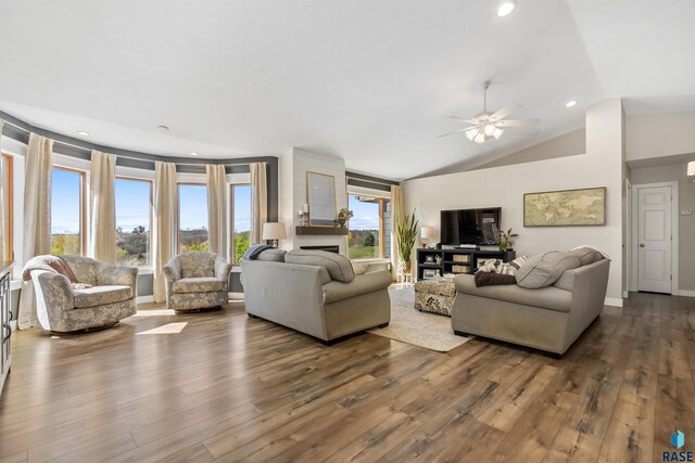 living area featuring a fireplace, a ceiling fan, baseboards, wood finished floors, and lofted ceiling