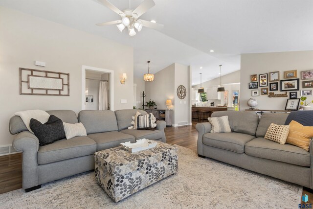 living room featuring baseboards, vaulted ceiling, wood finished floors, and visible vents
