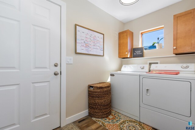 washroom with baseboards, washing machine and dryer, cabinet space, and wood finished floors
