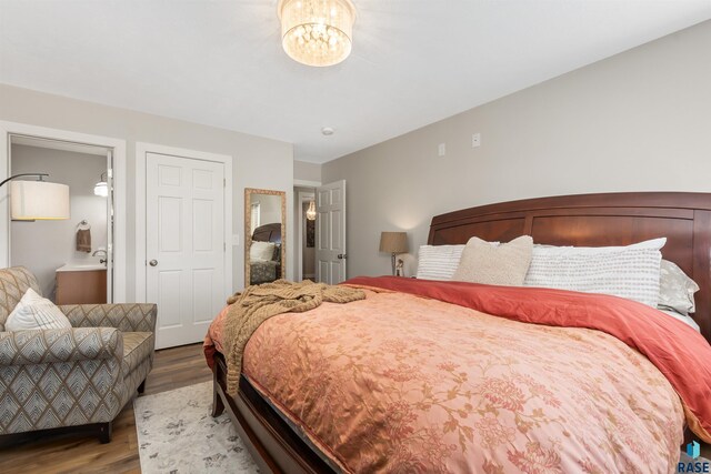 bedroom featuring a notable chandelier, wood finished floors, and ensuite bathroom