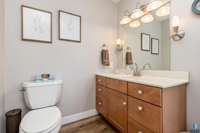 bathroom with toilet, baseboards, wood finished floors, and vanity
