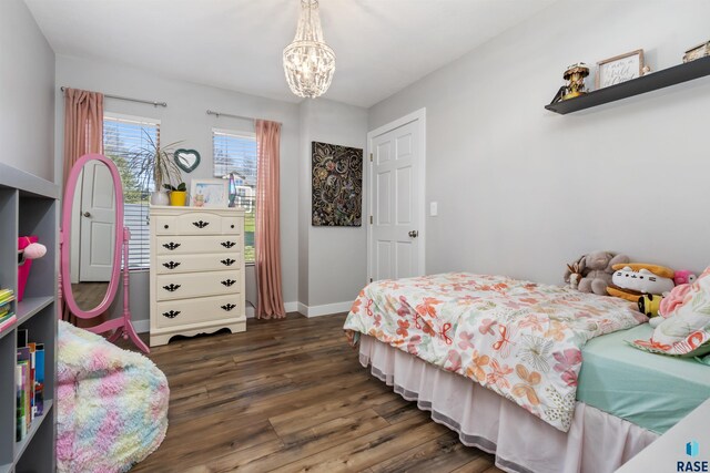 bedroom featuring baseboards, wood finished floors, and a chandelier