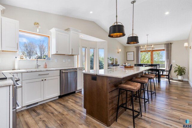 kitchen featuring white cabinetry, tasteful backsplash, a sink, appliances with stainless steel finishes, and vaulted ceiling