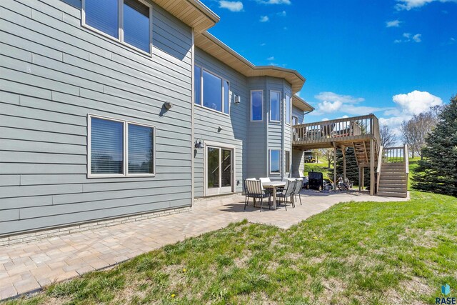 back of property featuring stairway, a yard, a wooden deck, and a patio area