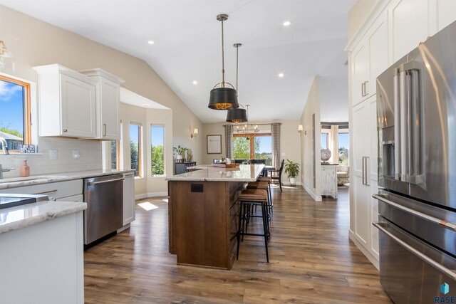 kitchen with a kitchen island, white cabinets, backsplash, vaulted ceiling, and stainless steel appliances