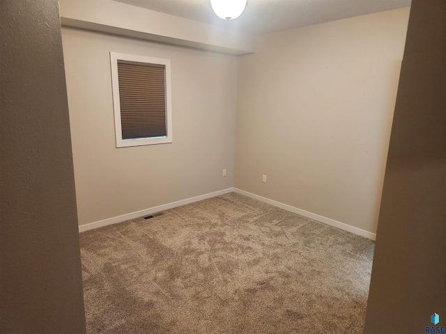 empty room featuring carpet floors, baseboards, and visible vents