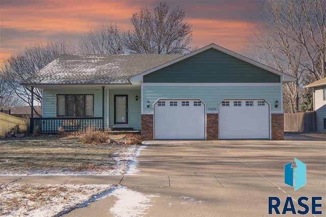 view of front of home with fence, an attached garage, brick siding, a porch, and concrete driveway