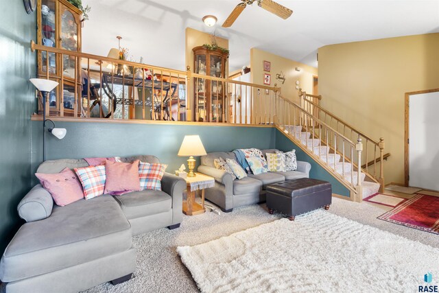 living room featuring vaulted ceiling, stairway, carpet, and a ceiling fan