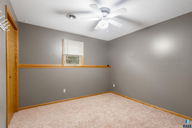 carpeted spare room with visible vents, a textured ceiling, and baseboards