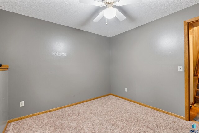 unfurnished room with carpet floors, a textured ceiling, baseboards, and ceiling fan