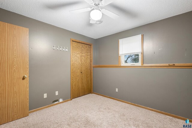 carpeted spare room featuring baseboards and a ceiling fan