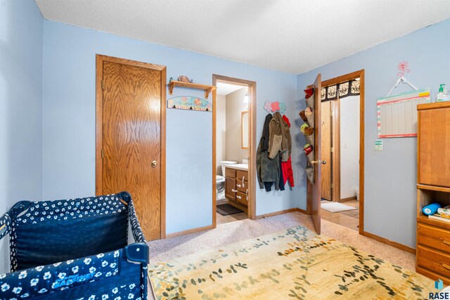carpeted bedroom with connected bathroom and baseboards
