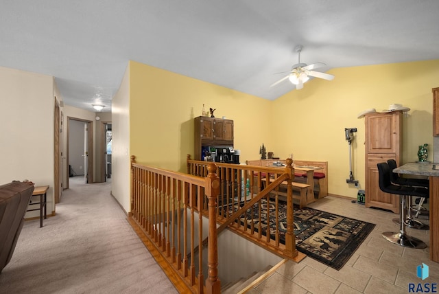 hallway featuring lofted ceiling, light tile patterned flooring, and an upstairs landing