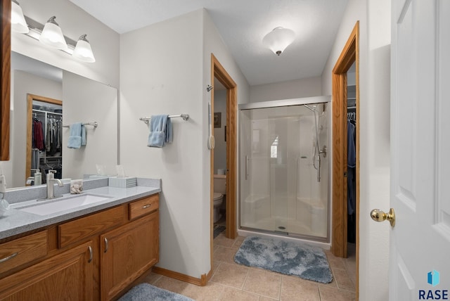 1012 E Magnolia Dr, Brandon, SD 57005 - bathroom with a shower stall, vanity, tile patterned floors, toilet, and a spacious closet