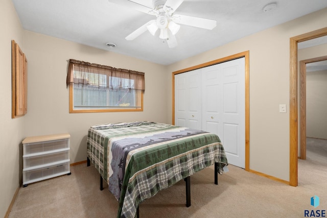 bedroom with baseboards, light colored carpet, ceiling fan, and a closet