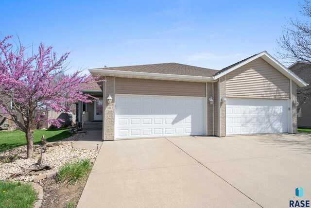 1012 E Magnolia Dr, Brandon, SD 57005 - view of front of house featuring concrete driveway, brick siding, an attached garage, and roof with shingles