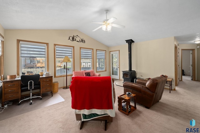 living room featuring a ceiling fan, light colored carpet, a healthy amount of sunlight, and a wood stove