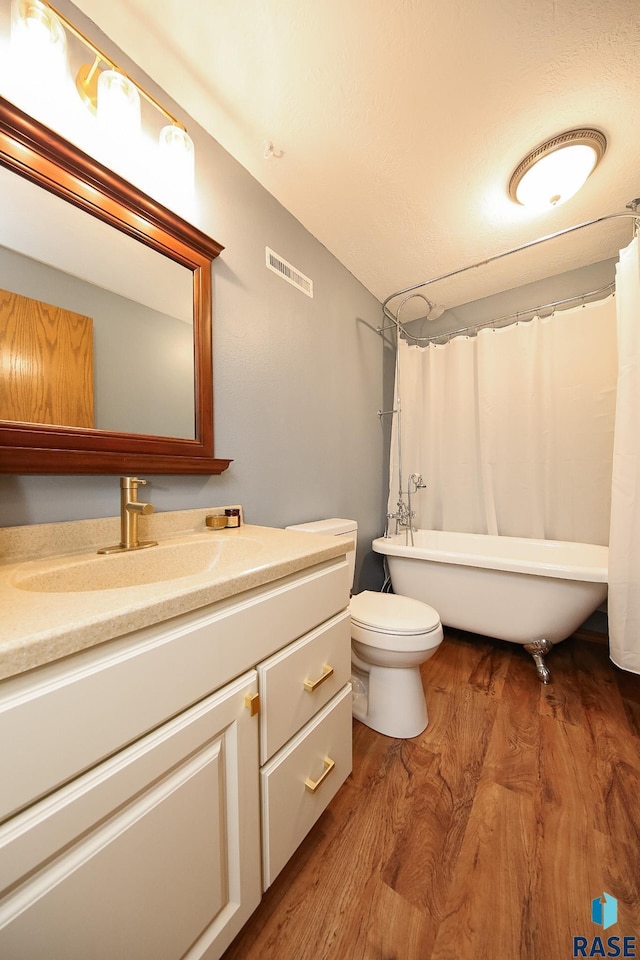 3219 S Grace Ave, Sioux Falls, SD 57103 - bathroom featuring vanity, toilet, wood finished floors, visible vents, and a soaking tub