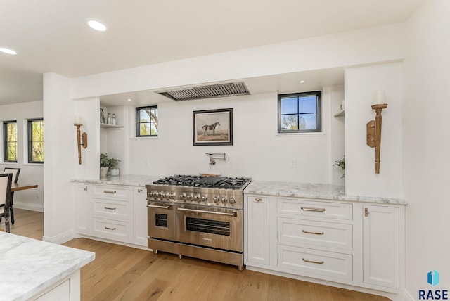 kitchen with white cabinets, light stone counters, range with two ovens, recessed lighting, and light wood-type flooring