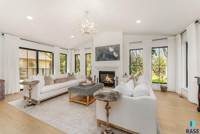 living room with a glass covered fireplace, vaulted ceiling, recessed lighting, and light wood-style flooring