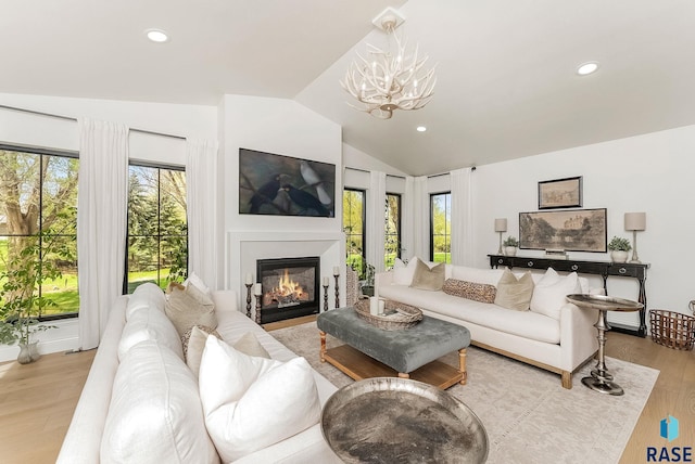 living room with recessed lighting, lofted ceiling, wood finished floors, and a notable chandelier