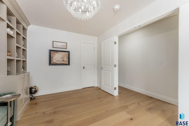 interior space with light wood-style floors, baseboards, and a chandelier