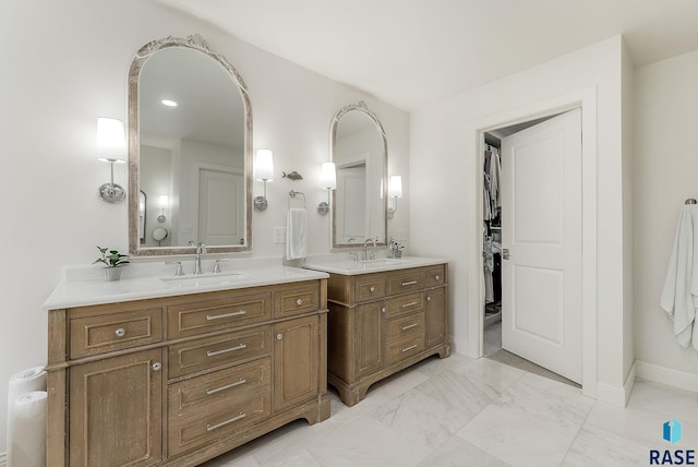 bathroom with baseboards, a sink, marble finish floor, and two vanities