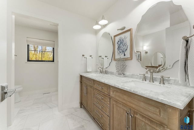 full bath featuring a sink, baseboards, toilet, and double vanity
