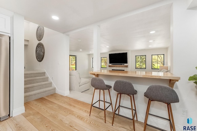 kitchen with recessed lighting, open floor plan, light wood finished floors, and a kitchen breakfast bar
