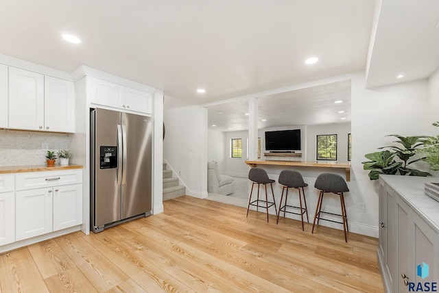 kitchen with stainless steel refrigerator with ice dispenser, recessed lighting, white cabinetry, and light wood-type flooring