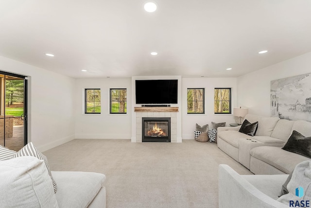 living area featuring recessed lighting, light carpet, a healthy amount of sunlight, and a tile fireplace
