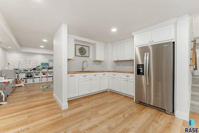 kitchen with white cabinetry, a sink, stainless steel fridge with ice dispenser, and light wood-style floors