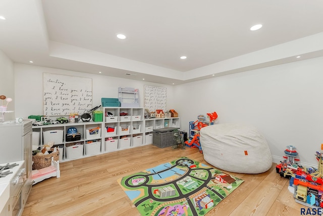 rec room with recessed lighting, a raised ceiling, and wood finished floors