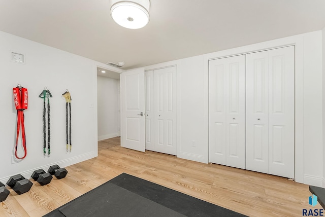 exercise area with light wood-style floors, baseboards, and visible vents
