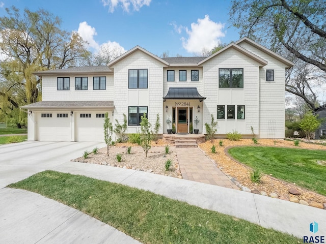view of front of home featuring a standing seam roof, driveway, metal roof, a front yard, and an attached garage