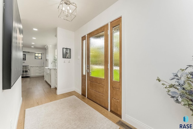 foyer entrance featuring recessed lighting, baseboards, a notable chandelier, and light wood-type flooring