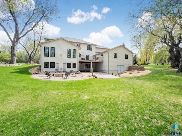 rear view of house with a lawn, a wooden deck, a fire pit, and a patio area
