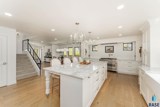 kitchen featuring a kitchen breakfast bar, recessed lighting, high end stainless steel range oven, and light wood-style floors