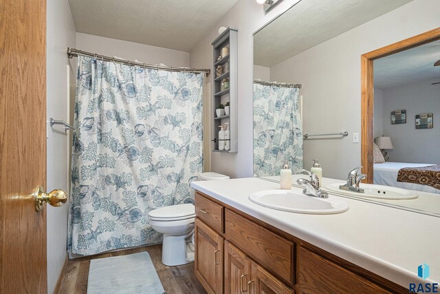 ensuite bathroom with vanity, wood finished floors, toilet, a shower with shower curtain, and ensuite bath