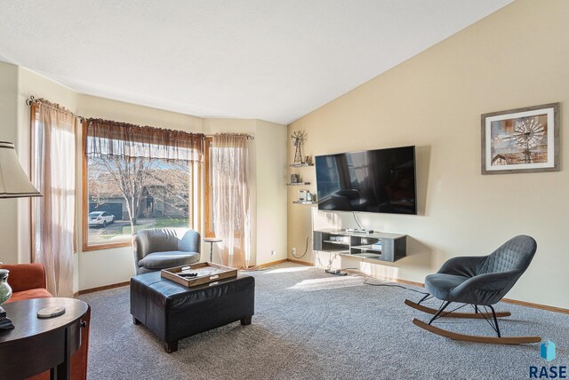 carpeted living area with baseboards and vaulted ceiling