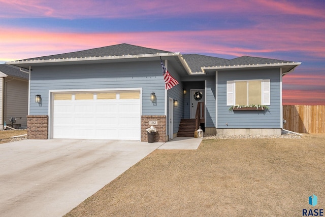 view of front of house featuring fence, a shingled roof, brick siding, a garage, and driveway