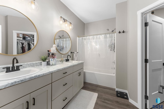 bathroom featuring double vanity, a sink, shower / bathtub combination with curtain, and wood finished floors