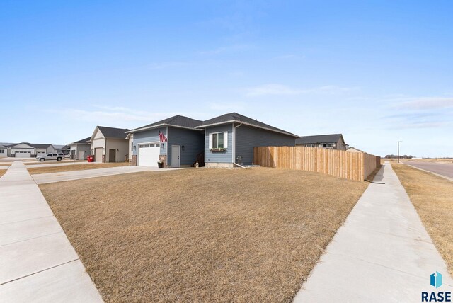 view of front facade with an attached garage, fence, and concrete driveway