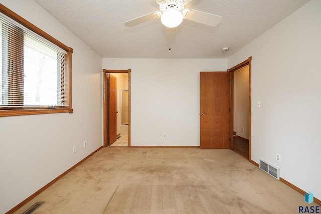 unfurnished bedroom featuring light carpet, a textured ceiling, and visible vents