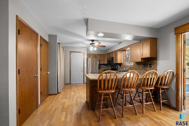 4108 E 23rd St, Sioux Falls, SD 57103 - kitchen with brown cabinets, stainless steel appliances, light wood-type flooring, and a peninsula
